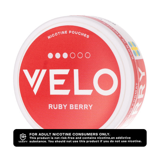 A round tin of VELO brand 'Ruby Berry' nicotine pouches, featuring a bold red and white label with the brand name 'VELO' in large white letters. A black warning label is positioned at the bottom of the image.